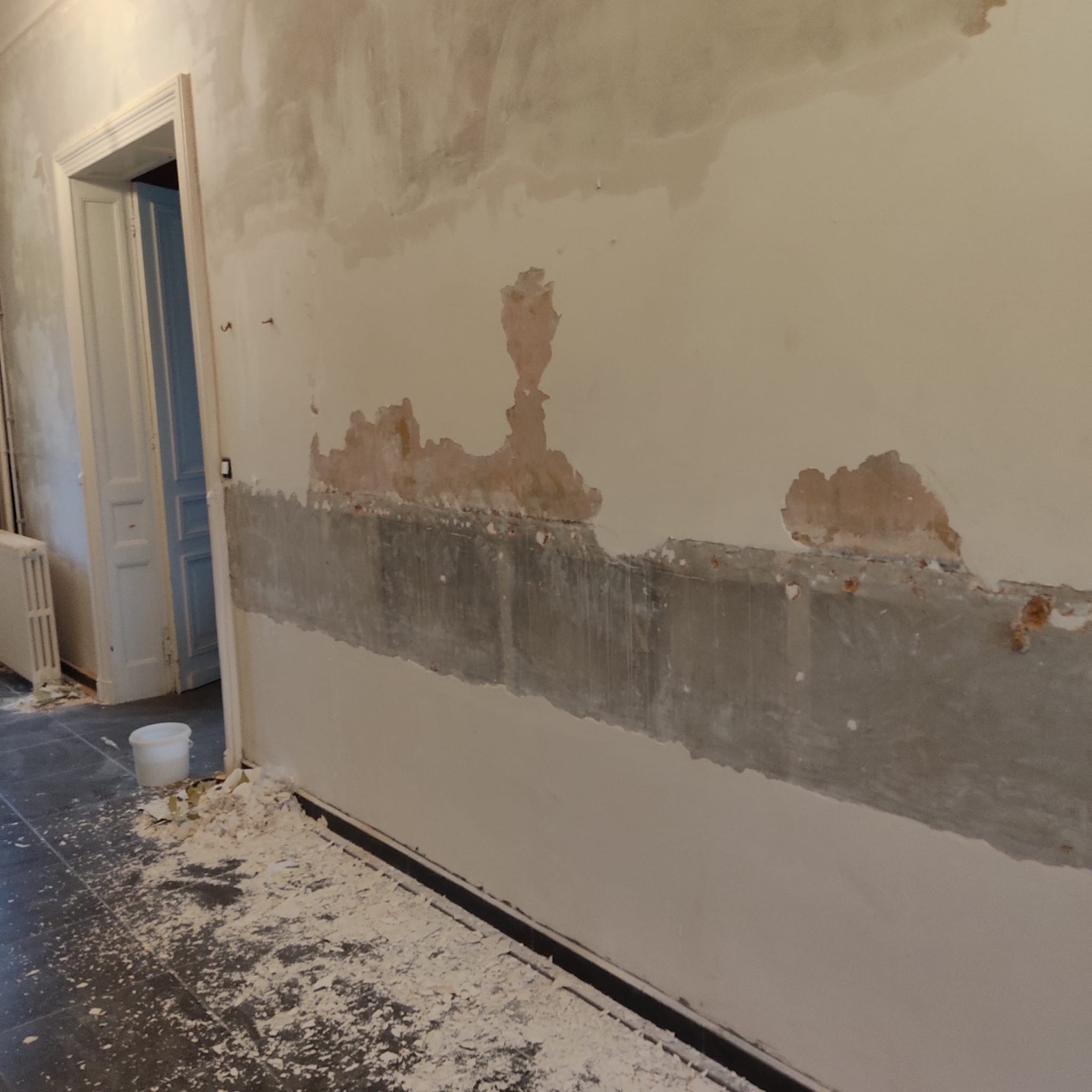 Mur ancien décapé jusqu'au support : traces d'humidité, anciens enduits et soubassement au ciment